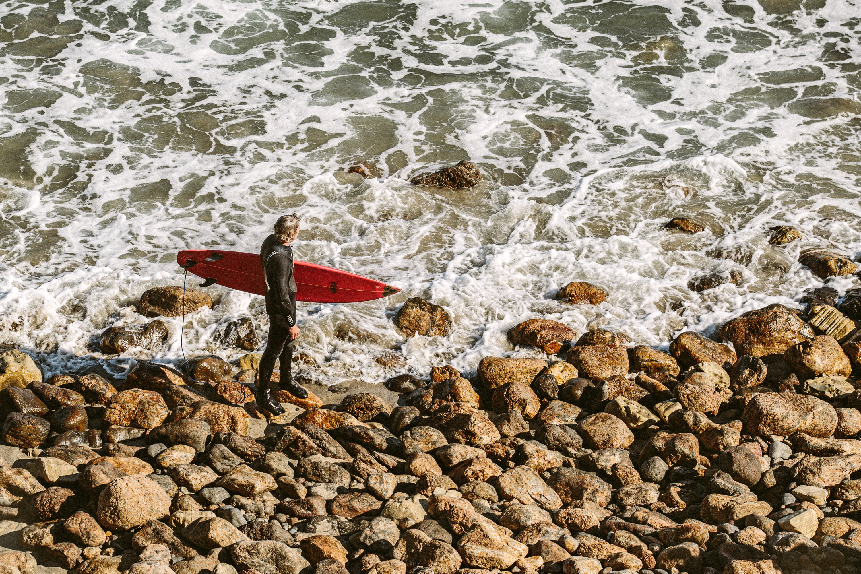 Surfer sizing up the waves at Point Dume State Beach, Malibu (Unsplash)