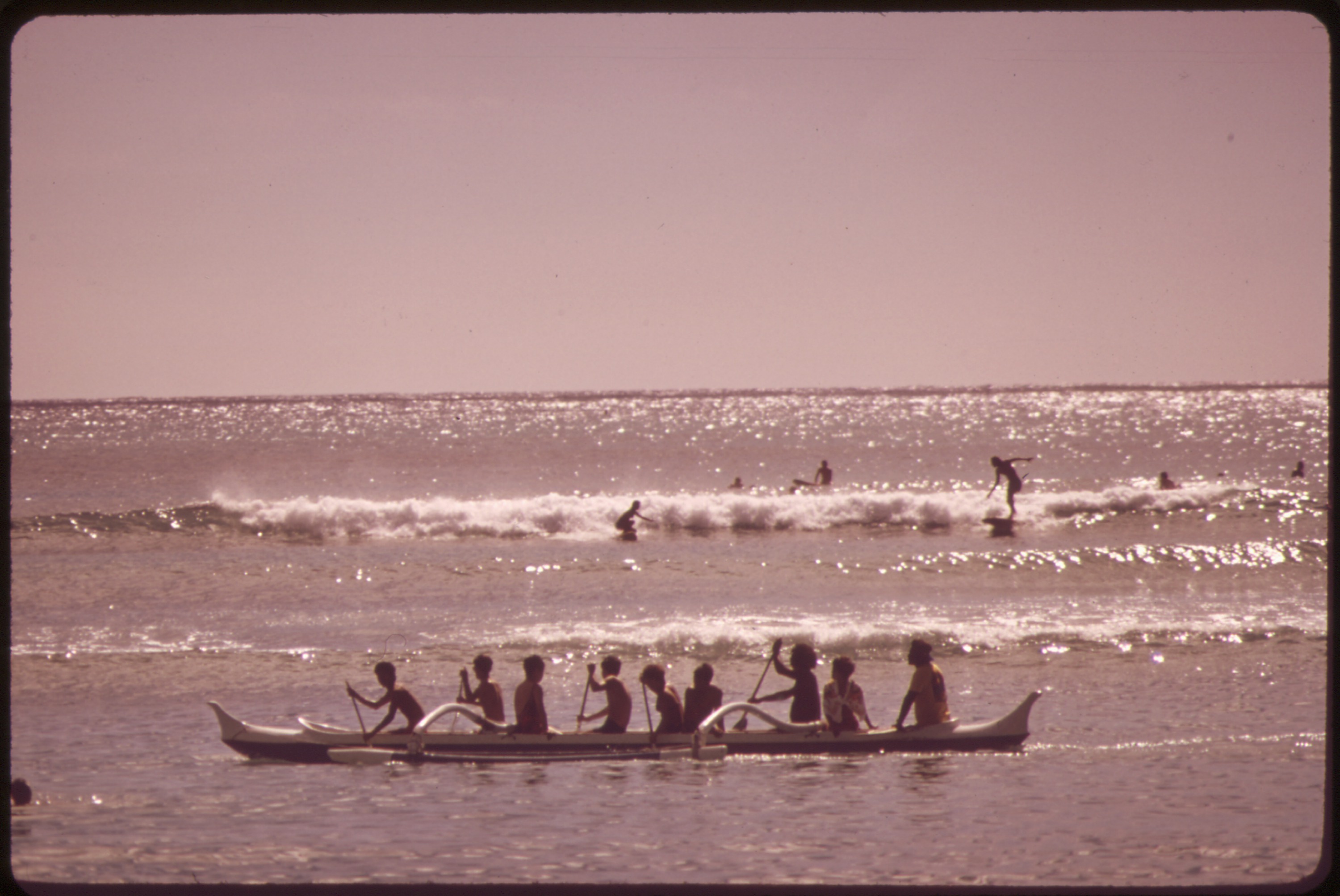 Outrigger canoes and surfers at Waikīkī Beach